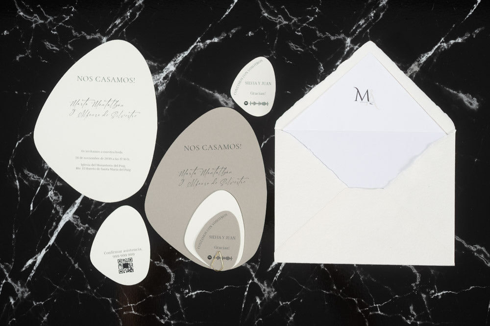 Set completo de invitaciones de boda en formato piedra orgánica color gris, con tarjetas principales, complementarias y sobre artesanal blanco con forro interior.