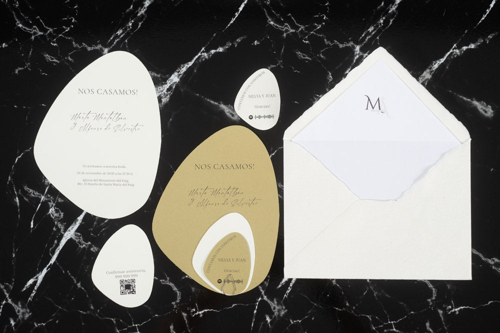 Set completo de invitaciones de boda en formato piedra orgánica color arena, con tarjetas principales, complementarias y sobre artesanal blanco con forro interior.