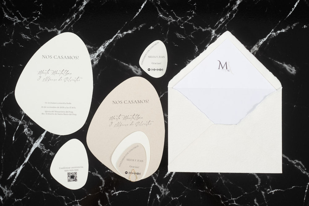 Set completo de invitaciones de boda en formato piedra color beige, con tarjetas principales y complementarias junto a sobre artesanal blanco con forro interior.