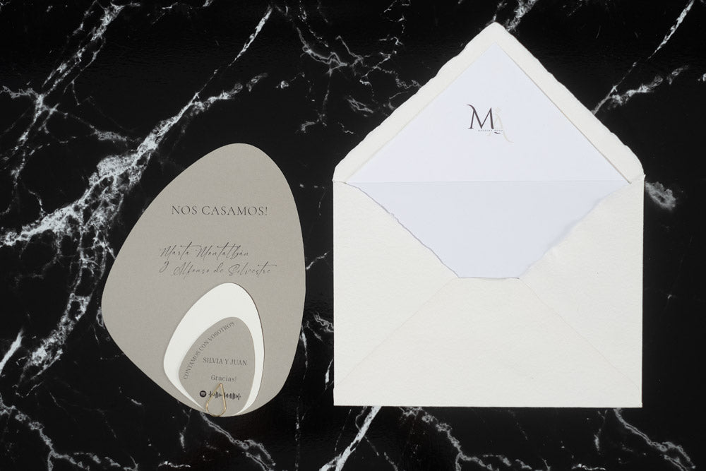 Invitación de boda en formato piedra color gris con tarjetas complementarias, acompañada de sobre artesanal blanco con forro interior.