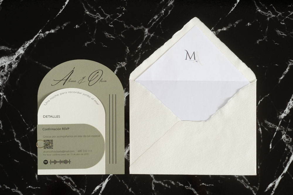 Invitación de boda modelo Aventurina en color oliva con diseño semicircular, detalles en blanco y tipografía elegante, presentada junto a sobre artesanal blanco con forro interior a juego.