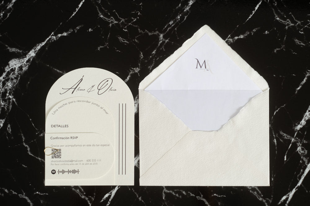 Invitación de boda Aventurina en color nieve, diseño semicircular con detalles modernos y tipografía elegante, presentada junto a sobre artesanal blanco con forro interior a juego.