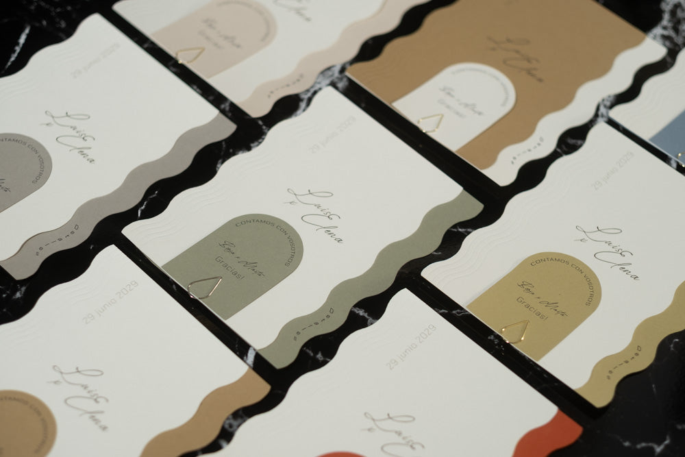 Variantes de color de la invitación de boda Berilio con diseño ondulado, disponibles en tonos naturales como arena, oliva, miel, terracota, ceniza y azul.
