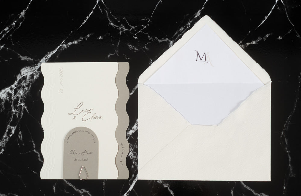 Invitación de boda Berilio en color ceniza con bordes ondulados, acompañada de sobre artesanal hecho a mano con forro interior blanco.
