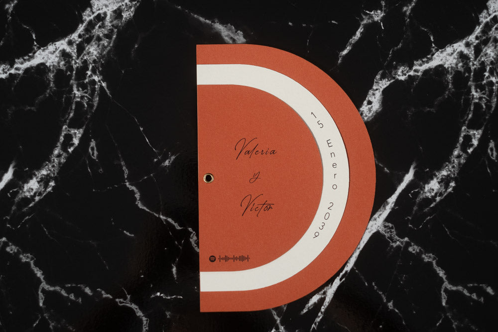 Invitación de boda modelo Cuarzo en color terracota semicircular cerrada, con los nombres de los novios y la fecha del enlace impresa en el borde exterior.
