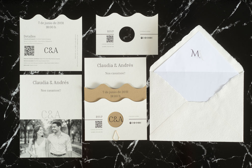 Set completo de la invitación de boda Jade en color arena, compuesto por tarjeta principal con diseño ondulado, tarjeta de detalles, tarjeta RSVP, tarjeta con fotografía de los novios y sobre artesanal hecho a mano con forro blanco.