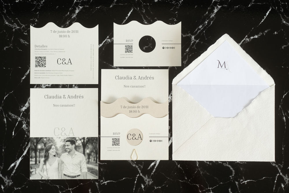 Set completo de la invitación de boda Jade en color marfil, compuesto por tarjeta principal con diseño ondulado, tarjeta de detalles, tarjeta RSVP, tarjeta con fotografía de los novios y sobre artesanal con forro interior blanco.