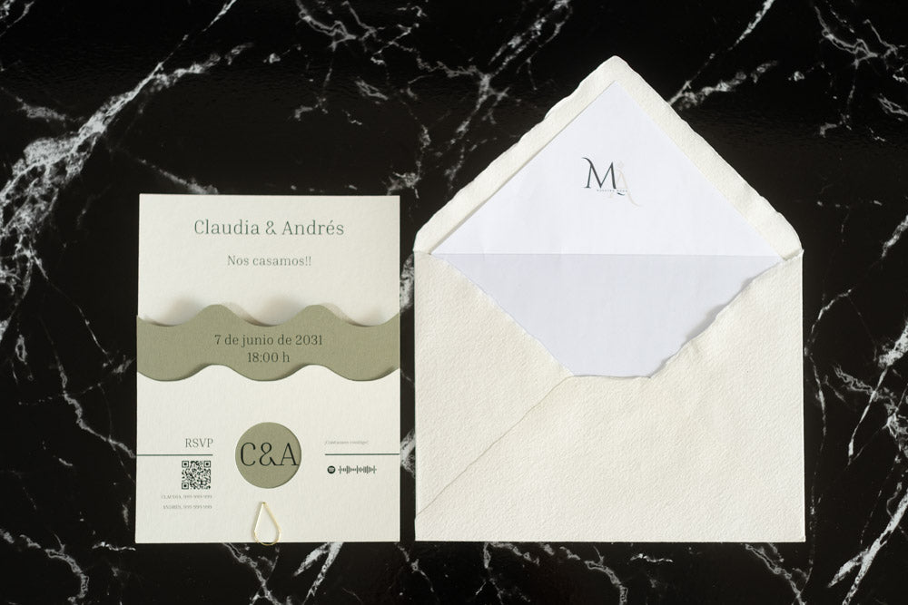 Invitación de boda Jade en color verde oliva con diseño ondulado, presentada junto al sobre artesanal hecho a mano con forro blanco.