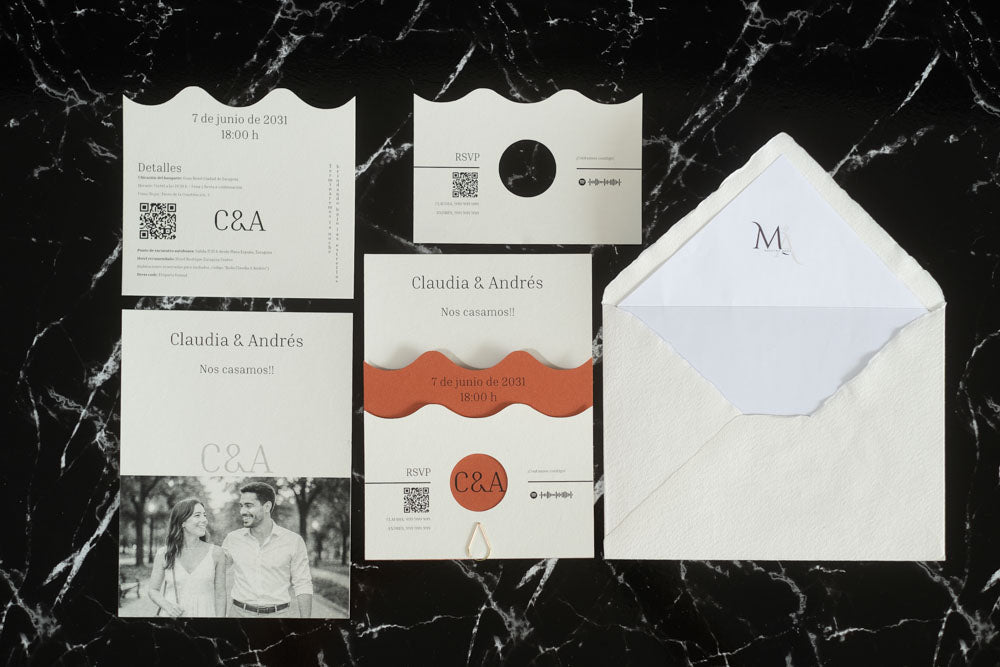 Set completo de la invitación de boda Jade en color terracota, con tarjeta principal ondulada, tarjeta de detalles, tarjeta RSVP, tarjeta con fotografía de los novios y sobre artesanal con forro interior blanco.