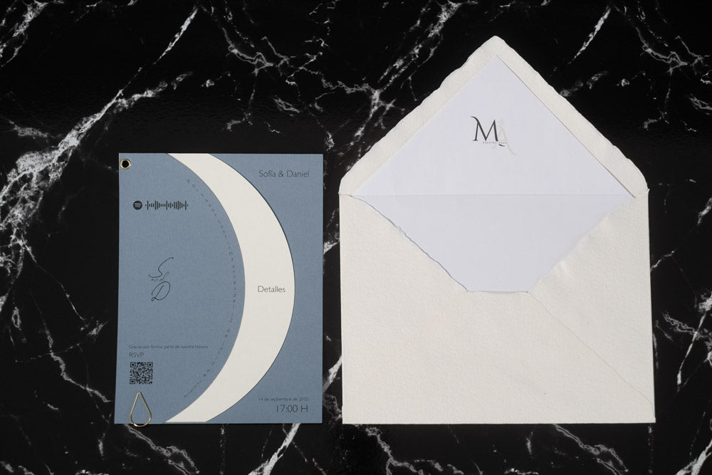 Invitación de boda Larimar color bruma con tarjeta semicircular giratoria y sobre artesanal con forro interior.