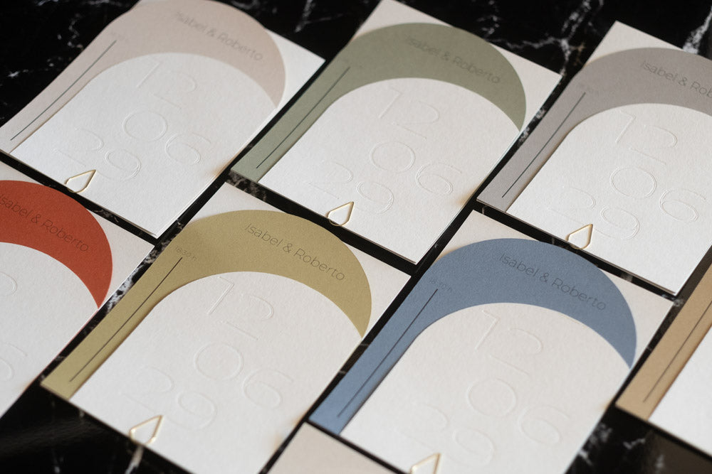 Invitaciones de boda modelo Ópalo en diferentes variantes de color —terracota, arena, oliva, miel, azul y ceniza— con diseño semicircular moderno, tipografía en relieve y acabado minimalista.