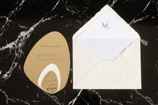 Invitación de boda en formato piedra color mostaza con tarjetas complementarias, junto a sobre artesanal blanco con forro interior.