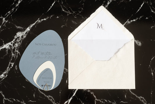 Invitación de boda en formato piedra color azul con tarjetas complementarias, acompañada de sobre artesanal blanco con forro interior.