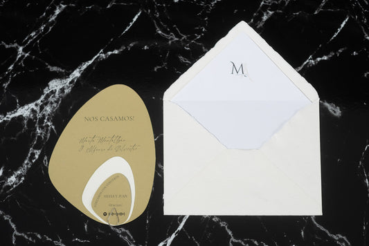 Invitación de boda en formato piedra color arena con tarjetas complementarias, acompañada de sobre artesanal blanco con forro interior.