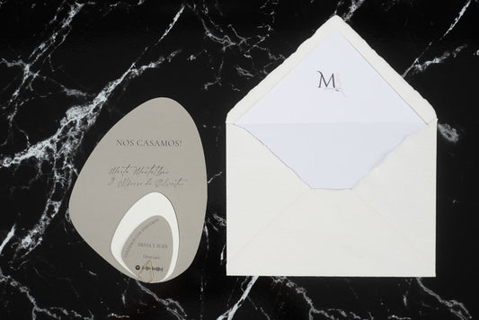 Invitación de boda en formato piedra color gris con tarjetas complementarias, acompañada de sobre artesanal blanco con forro interior.
