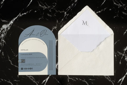 Invitación de boda modelo Aventurina en color azul con tipografía elegante y detalles en blanco, acompañada de sobre artesanal blanco con forro interior personalizado con iniciales.