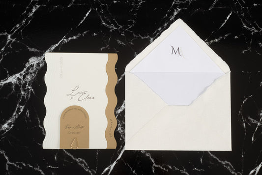 Invitación de boda Berilio en color arena con bordes ondulados, acompañada de sobre artesanal hecho a mano con forro interior blanco.