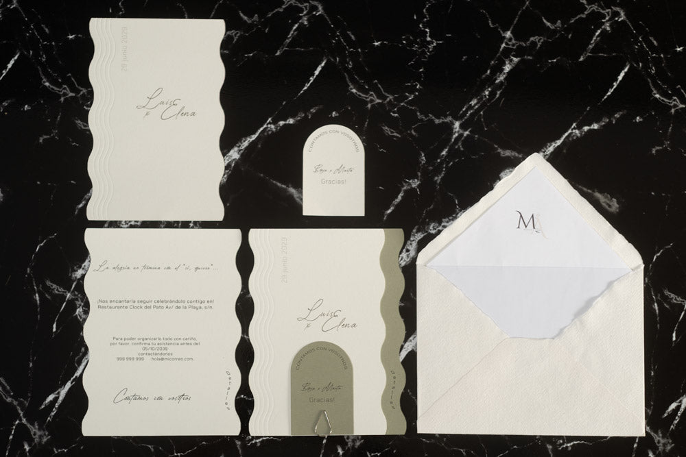 Set completo de la invitación de boda Berilio en color verde oliva con diseño ondulado, compuesto por tarjetas principales y complementarias, tarjeta de agradecimiento y sobre artesanal blanco con forro interior personalizado.