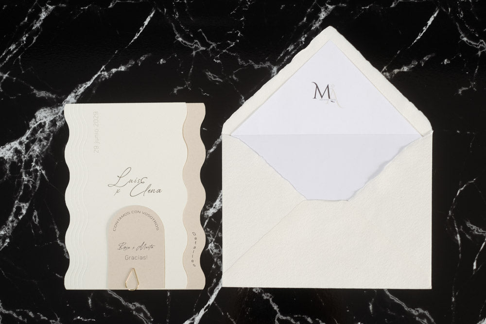 Invitación de boda Berilio en tonos  marfil con diseño de ondas laterales, tarjeta sujeta con clip dorado y sobre artesanal blanco con forro interior personalizado.