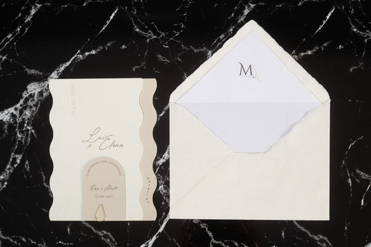 Invitación de boda Berilio en tonos  marfil con diseño de ondas laterales, tarjeta sujeta con clip dorado y sobre artesanal blanco con forro interior personalizado.