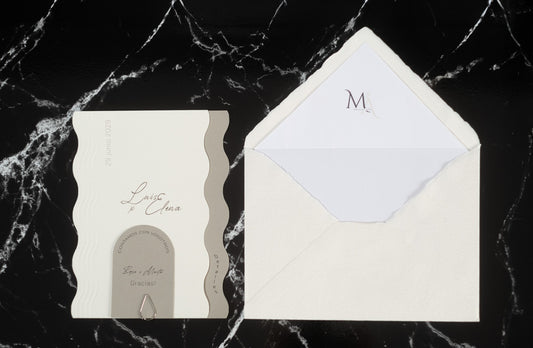 Invitación de boda Berilio en color ceniza con bordes ondulados, acompañada de sobre artesanal hecho a mano con forro interior blanco.