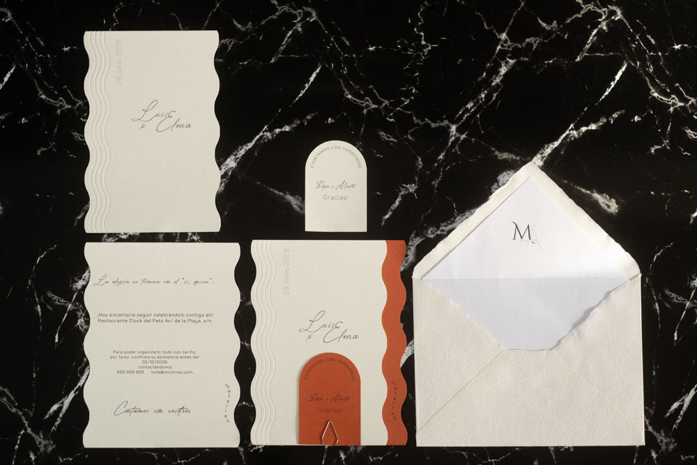Set completo de la invitación de boda Berilio en tonos terracota y blanco con tarjetas principales, complementarias y de agradecimiento, acompañado de sobre artesanal blanco con forro interior.