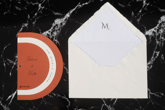 Invitación de boda modelo Cuarzo en color terracota semicircular cerrada, con los nombres de los novios y la fecha del enlace impresa en el borde exterior. Con Sobre blanco forrado.