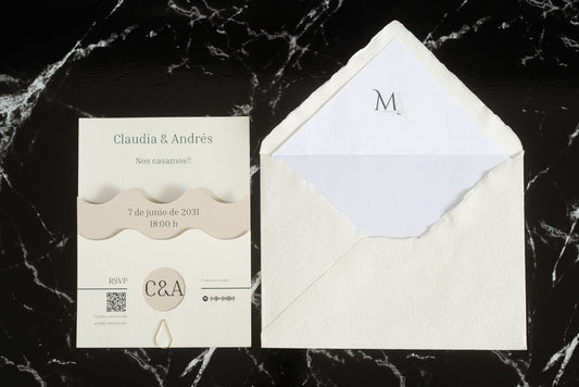 Invitación de boda Jade en color marfil con diseño ondulado y detalles en papel natural, acompañada de sobre artesanal hecho a mano con forro blanco.