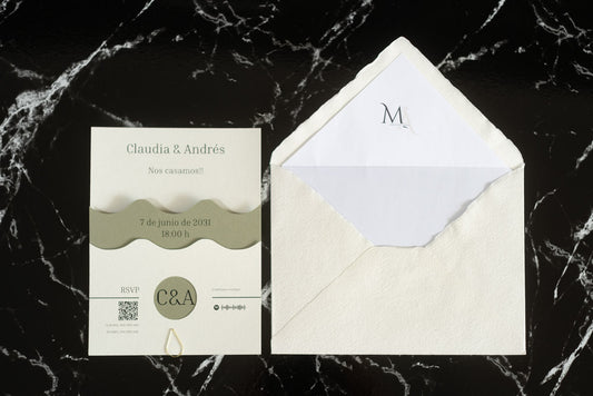 Invitación de boda Jade en color verde oliva con diseño ondulado, presentada junto al sobre artesanal hecho a mano con forro blanco.