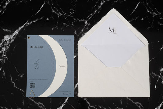 Invitación de boda Larimar color bruma con tarjeta semicircular giratoria y sobre artesanal con forro interior.