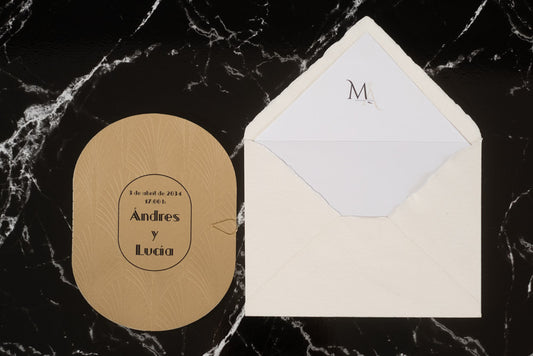 Invitación de boda Ónix en tono arena con tipografía elegante en negro, presentada junto a sobre artesanal blanco con forro interior personalizado.