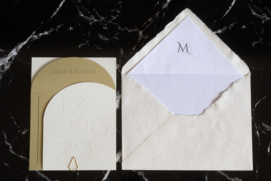 Invitación de boda semicircular en tono miel con textura grabada y tipografía negra, acompañada de sobre artesanal blanco con forro interior personalizado.
